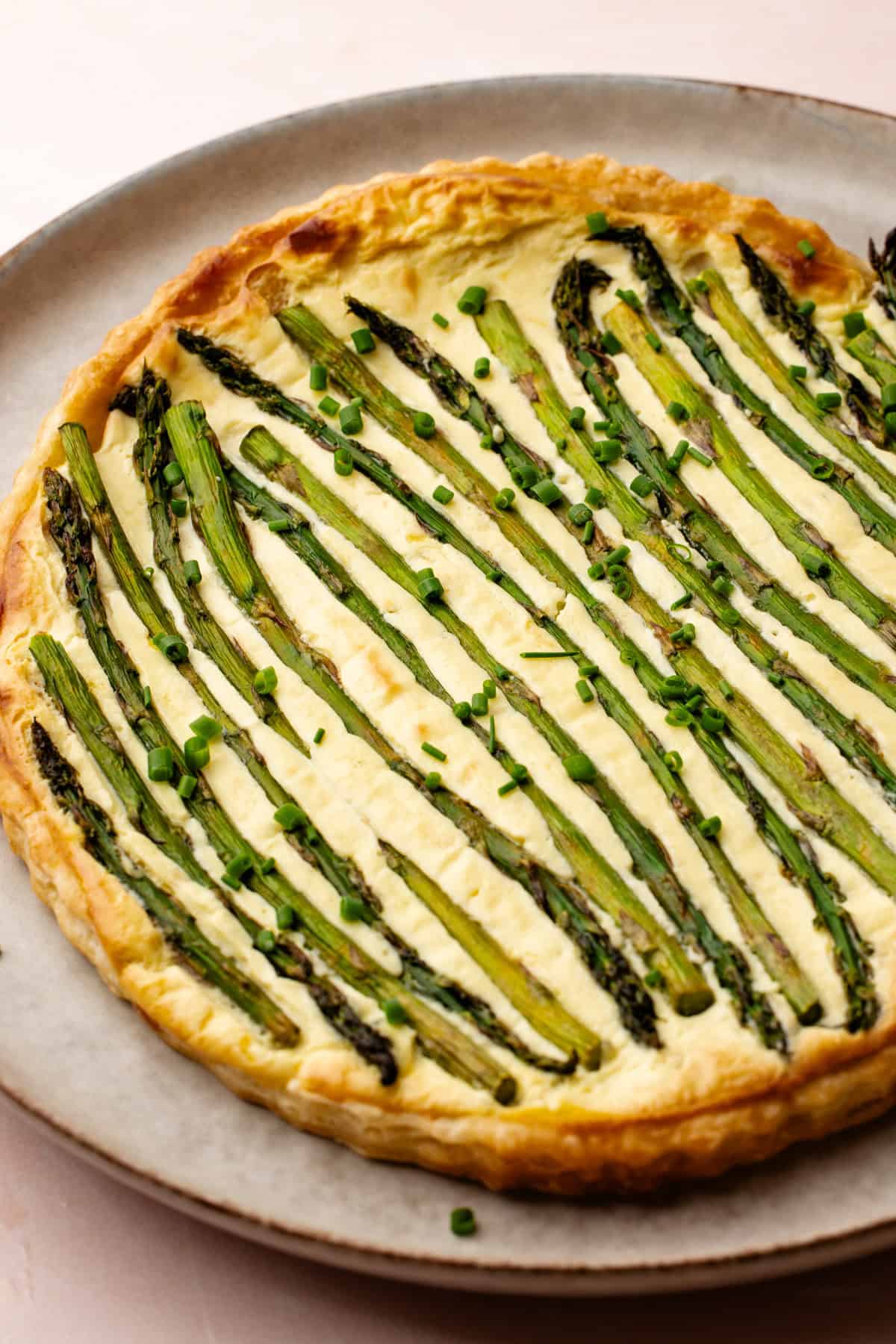 Tarte aux asperges au citron avec des asperges rôties et de la ciboulette hachée.