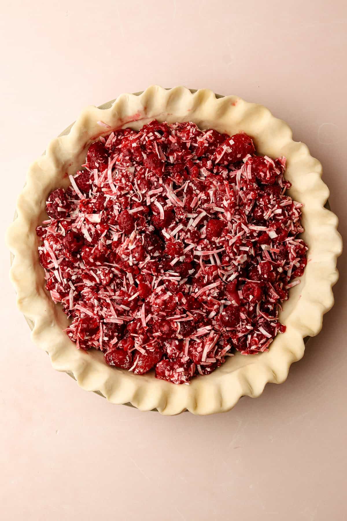 An assembled but unbaked raspberry coconut macaroon pie.