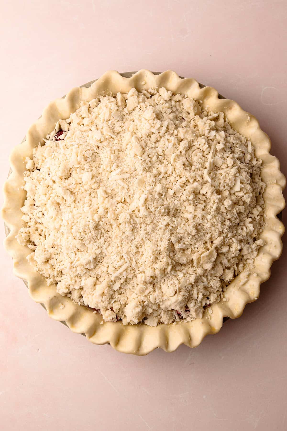 An unbaked raspberry pie with a coconut macaroon streusel on top.