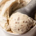 A pint container of homemade grapenut ice cream with a scoop in it.