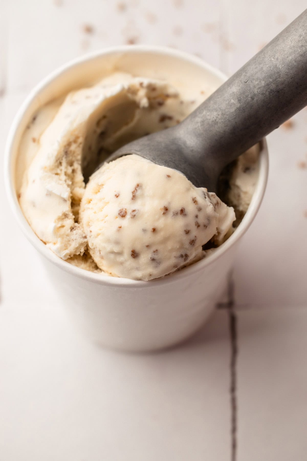 A pint container of homemade grapenut ice cream with a scoop in it.