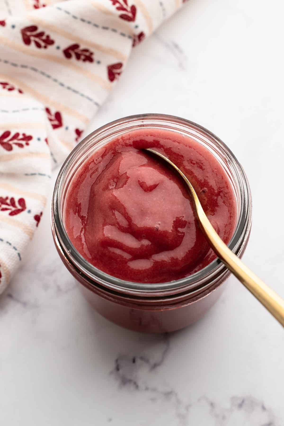 Vibrant red prepared Rhubarb coulis in a jar.