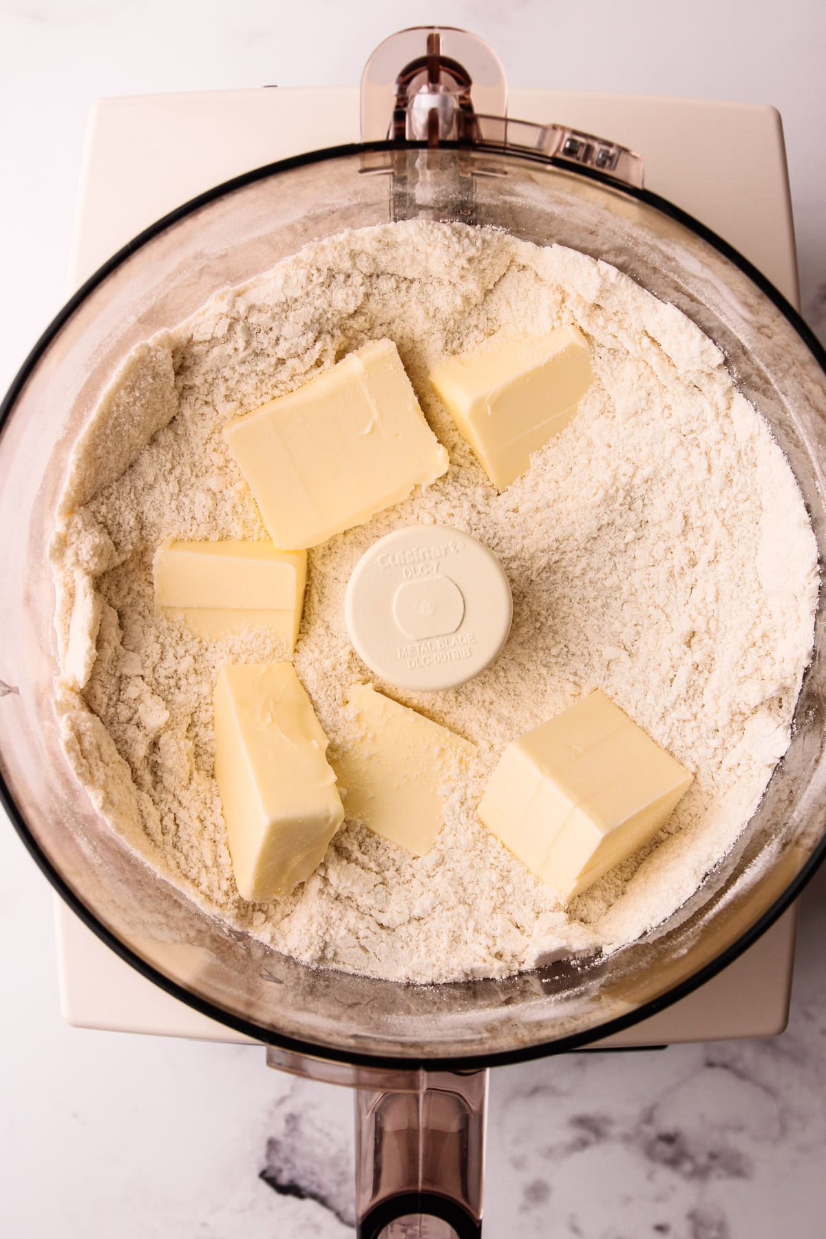 A mixture of almond flour and other dry ingredients and chunks of butter in a food processor for rhubarb crumb bars.