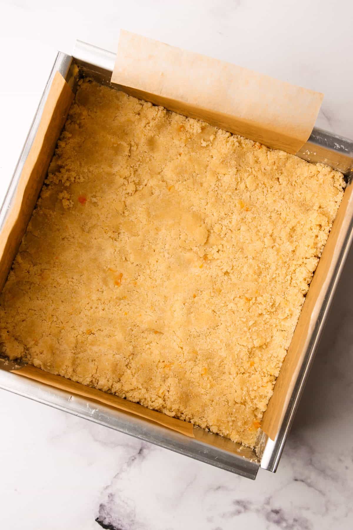 The bottom layer of an almond shortbread base unbaked.