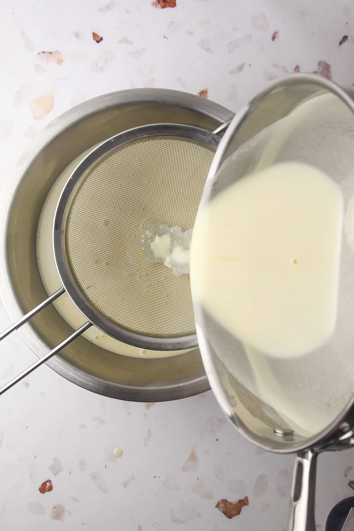 Straining a cooked french vanilla custard base for homemade french vanilla ice cream.