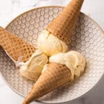 Three ice cream cones with homemade french vanilla ice cream inside of a bowl.