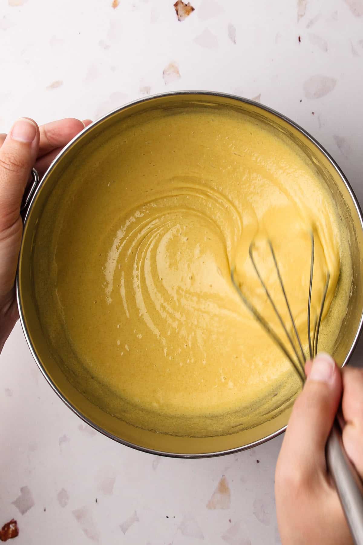 Egg yolks and sugar being whisked together in a bowl for homemade french vanilla ice cream.