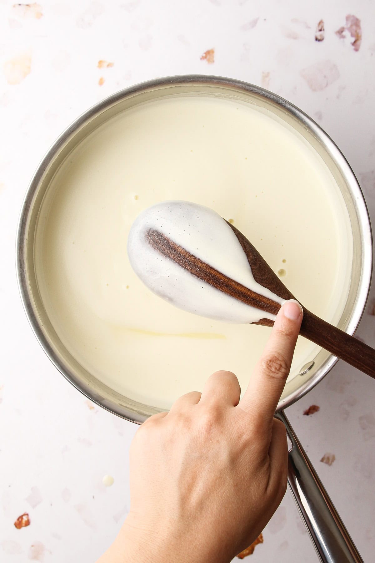 A cooked custard for french vanilla ice cream as indicated by the clean line held on a wooden spoon.