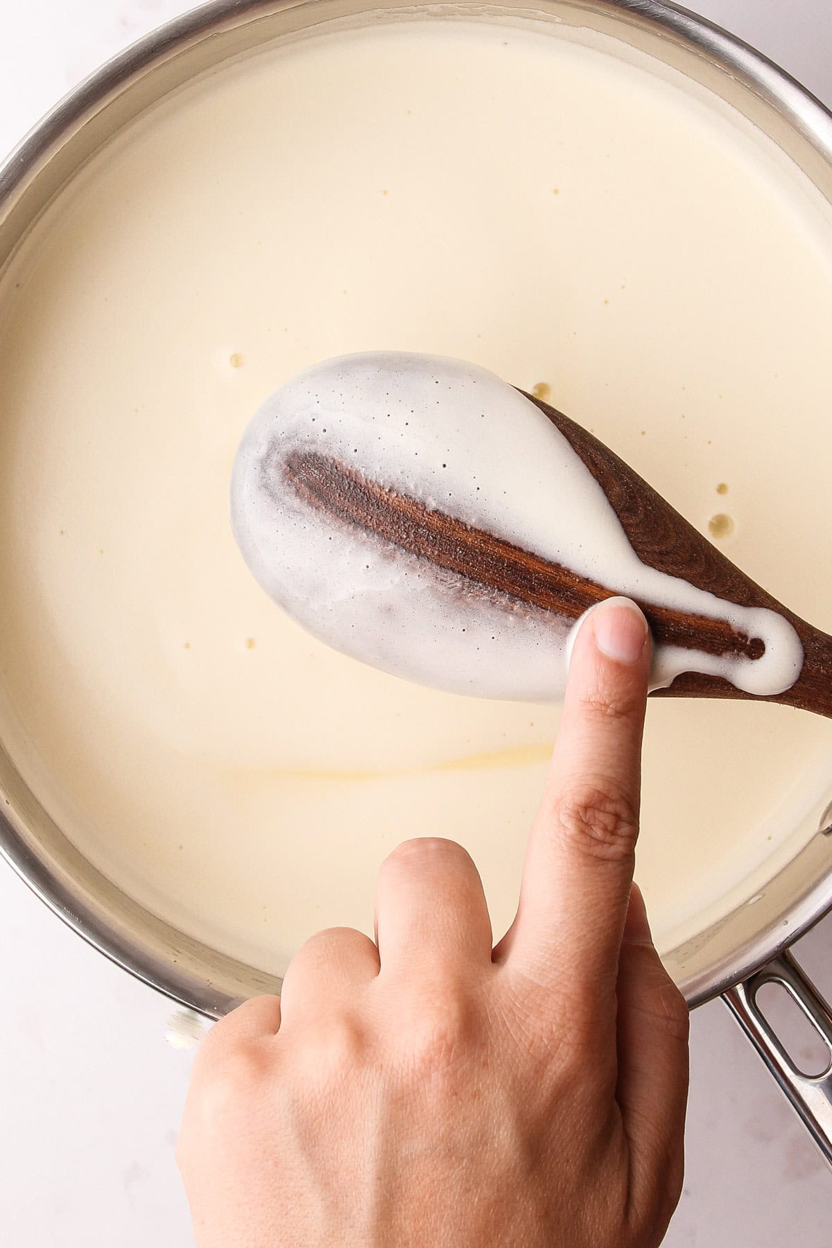 A properly set custard showing a line cleanly drawn on the back of the wooden spoon.