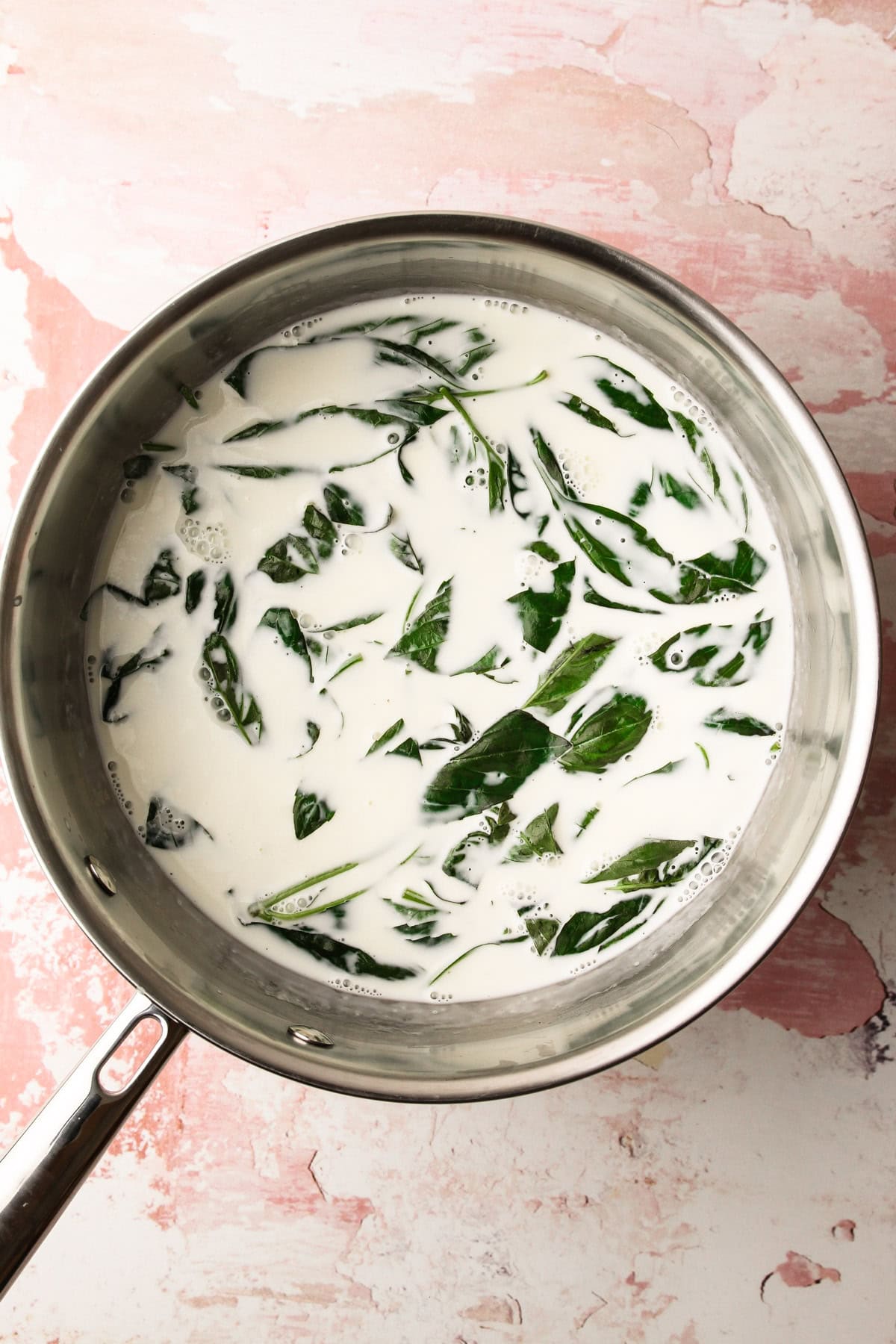 Fresh basil leaves steeping in a pot of milk for basil ice cream.