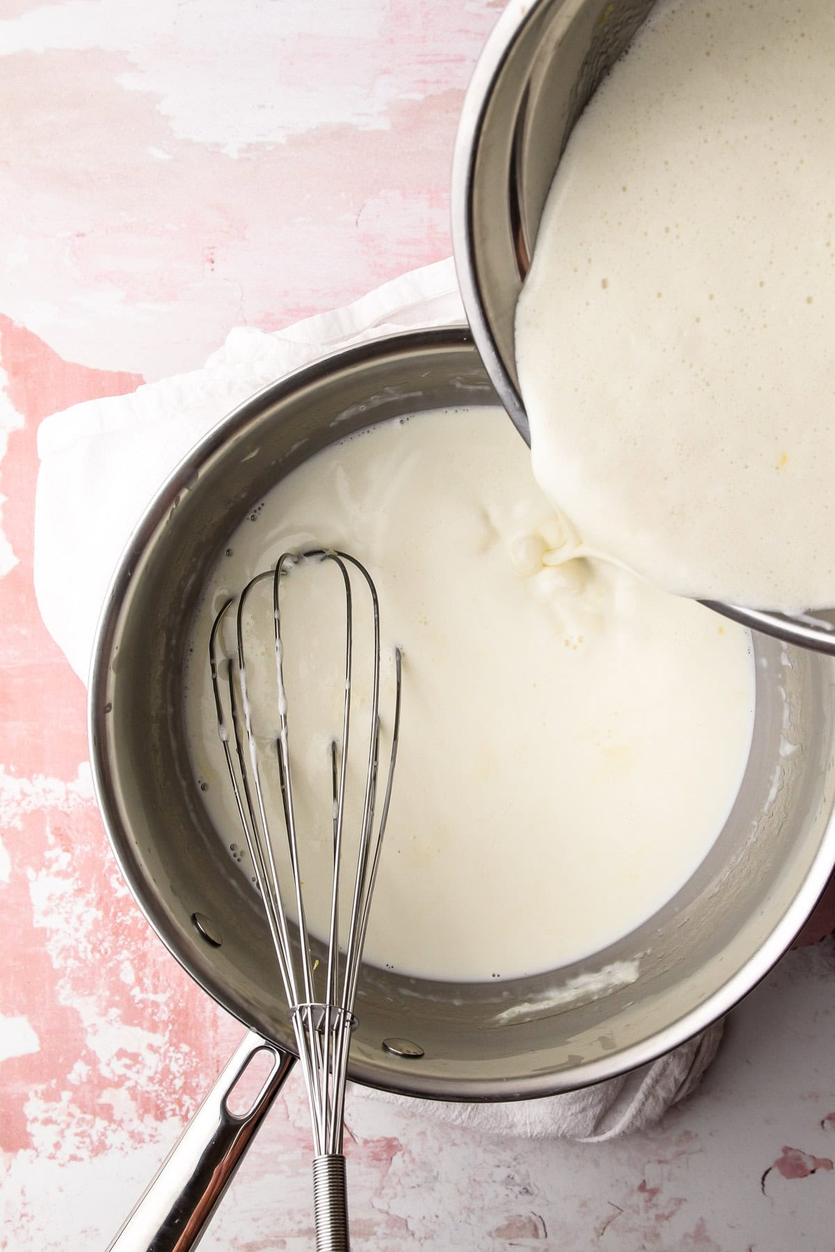 Pouring the basil cream into the egg mixture for homemade basil ice cream.