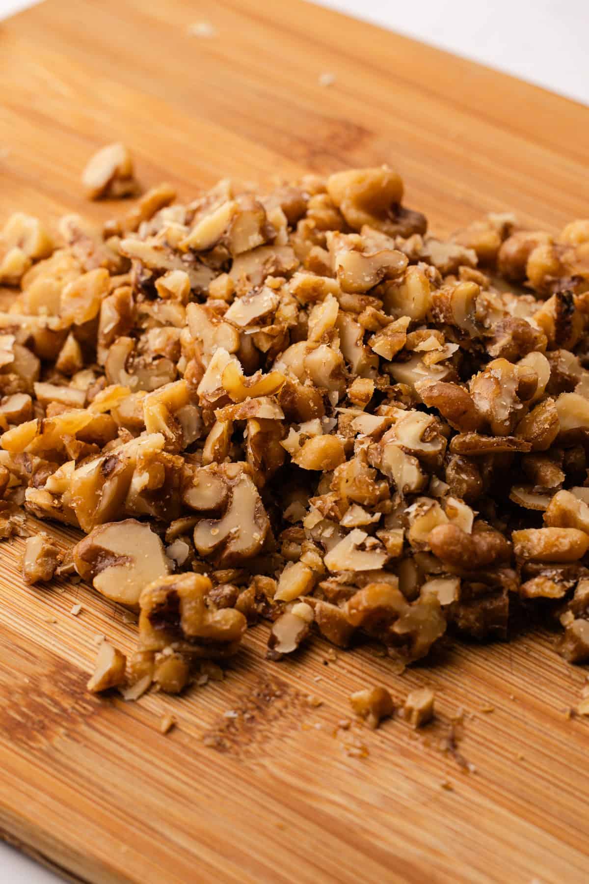 Chopped candied nuts on a cutting board for homemade maple walnut ice cream.