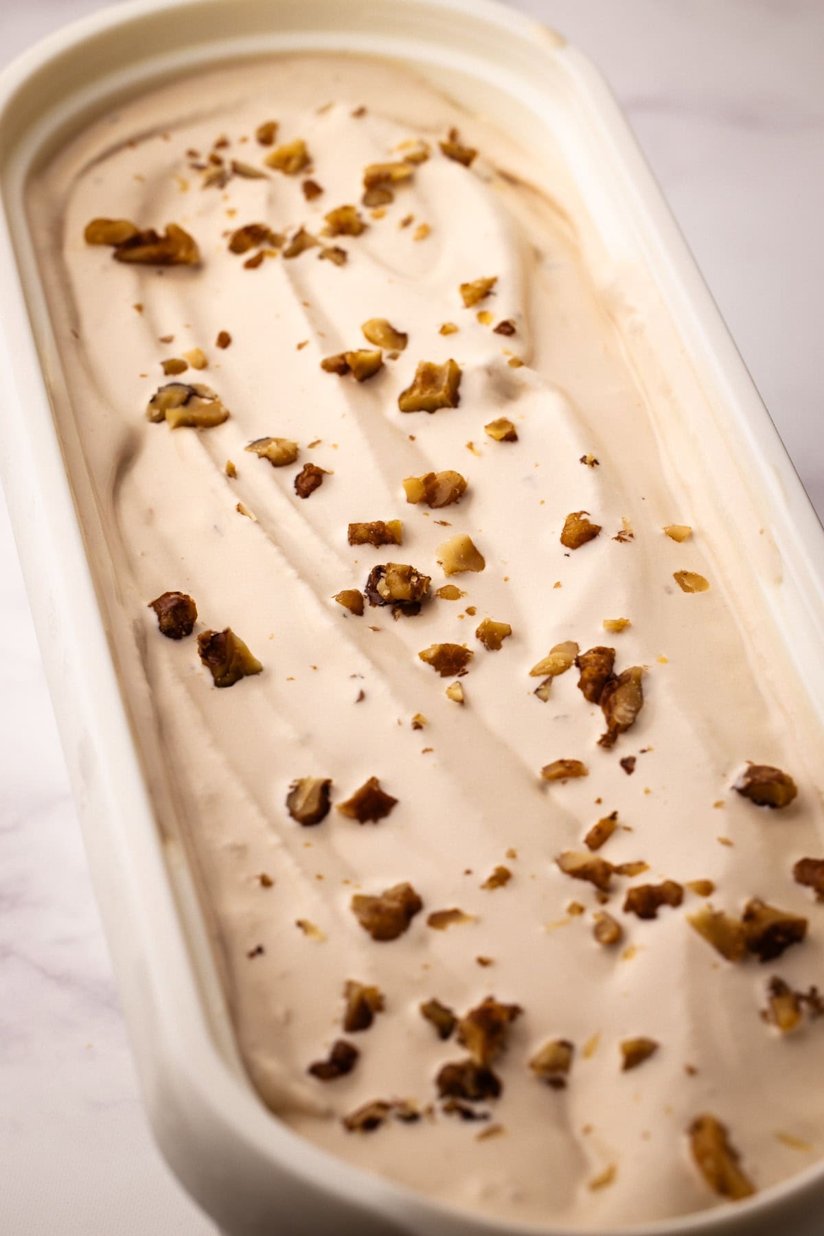 Homemade maple walnut ice cream in an ice cream container.