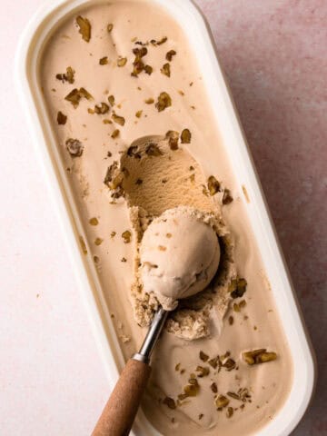 An ice cream scoop filled with a creamy scoop of maple walnut ice cream.