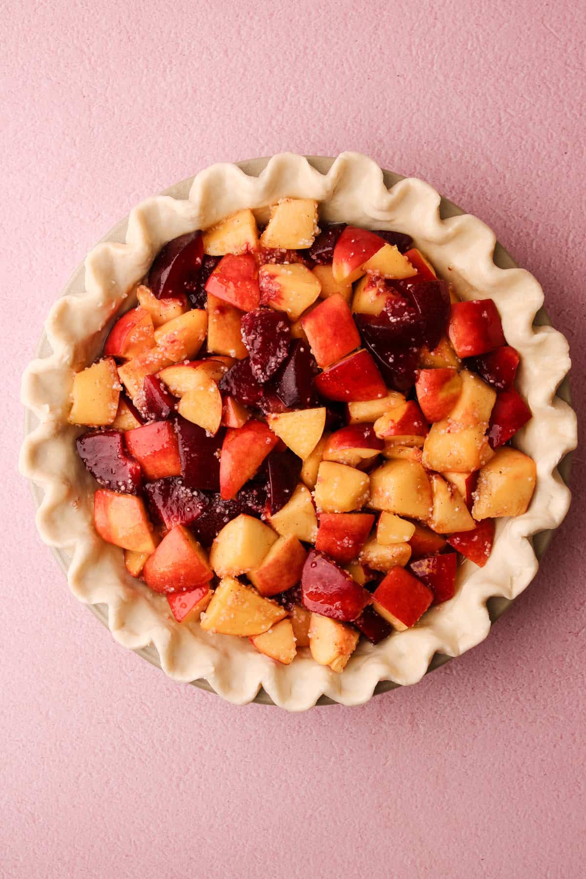 An unbaked nectarine plum pie waiting for the brown sugar crumble topping.