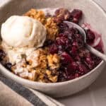 A serving of baked apple blueberry crisp with a scoop of ice cream in a bowl.