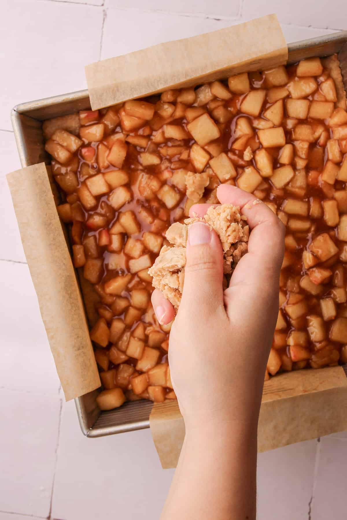 Crumbling the shortbread on top of the apple pie filling.