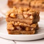 Two apple pie bars stacked up on a plate.