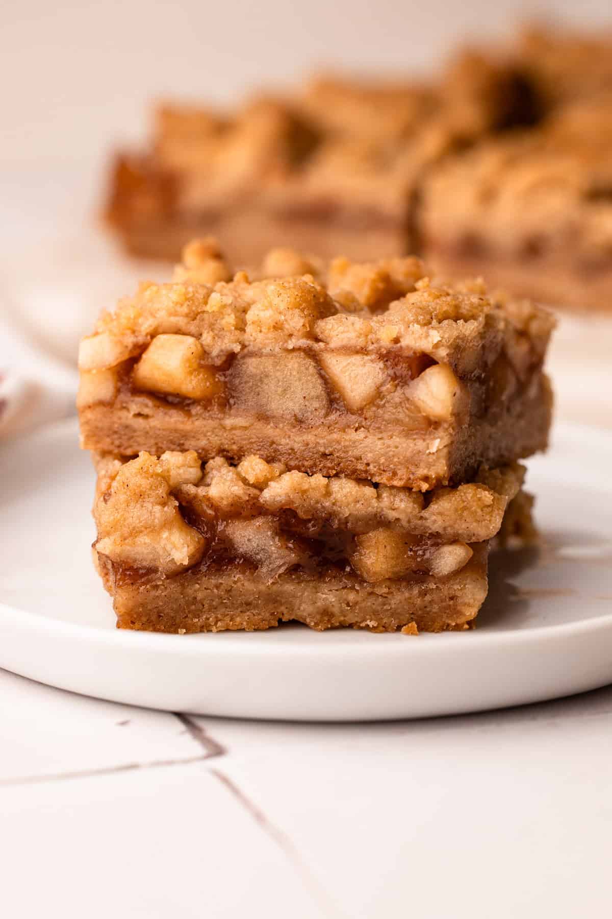 Two apple pie bars stacked up on a plate.