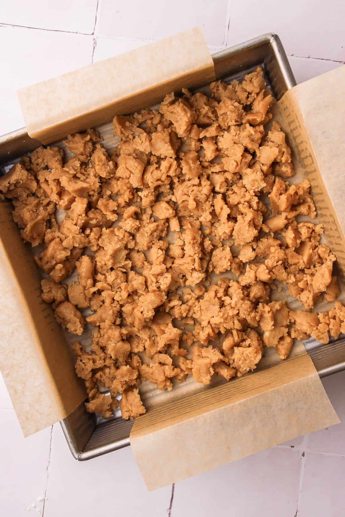 Crumbling the shortbread in a square pan.