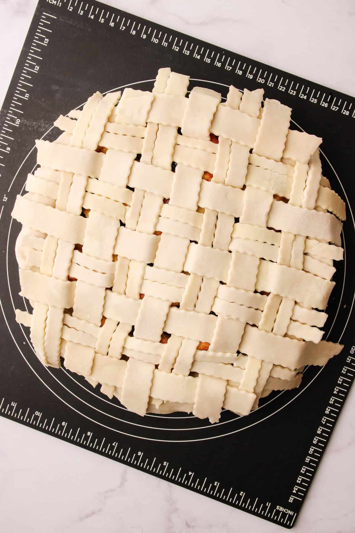 An unbaked lattice on top of a peach blueberry pie.