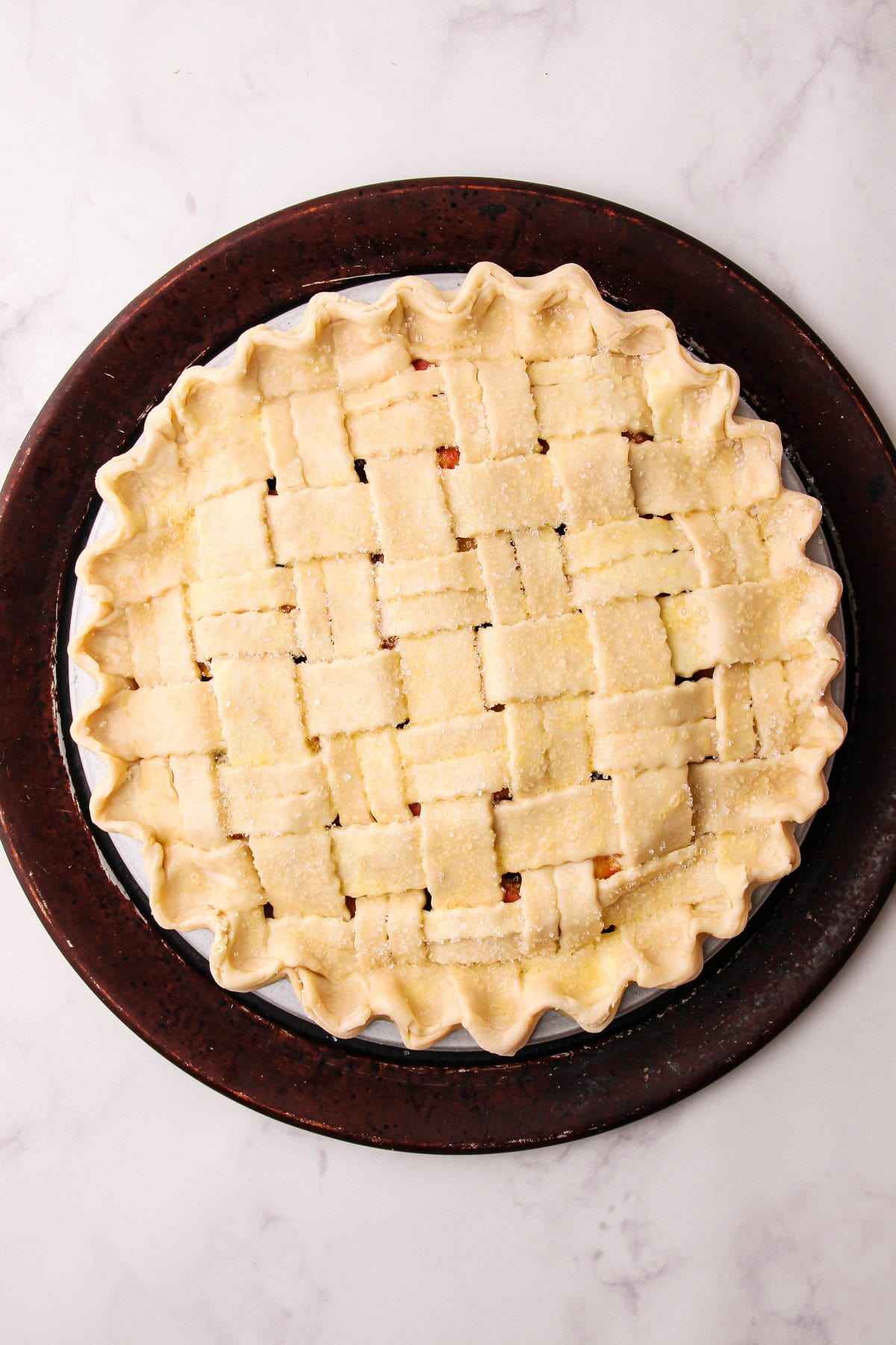 An unbaked peach blueberry pie with an egg wash and sugar.