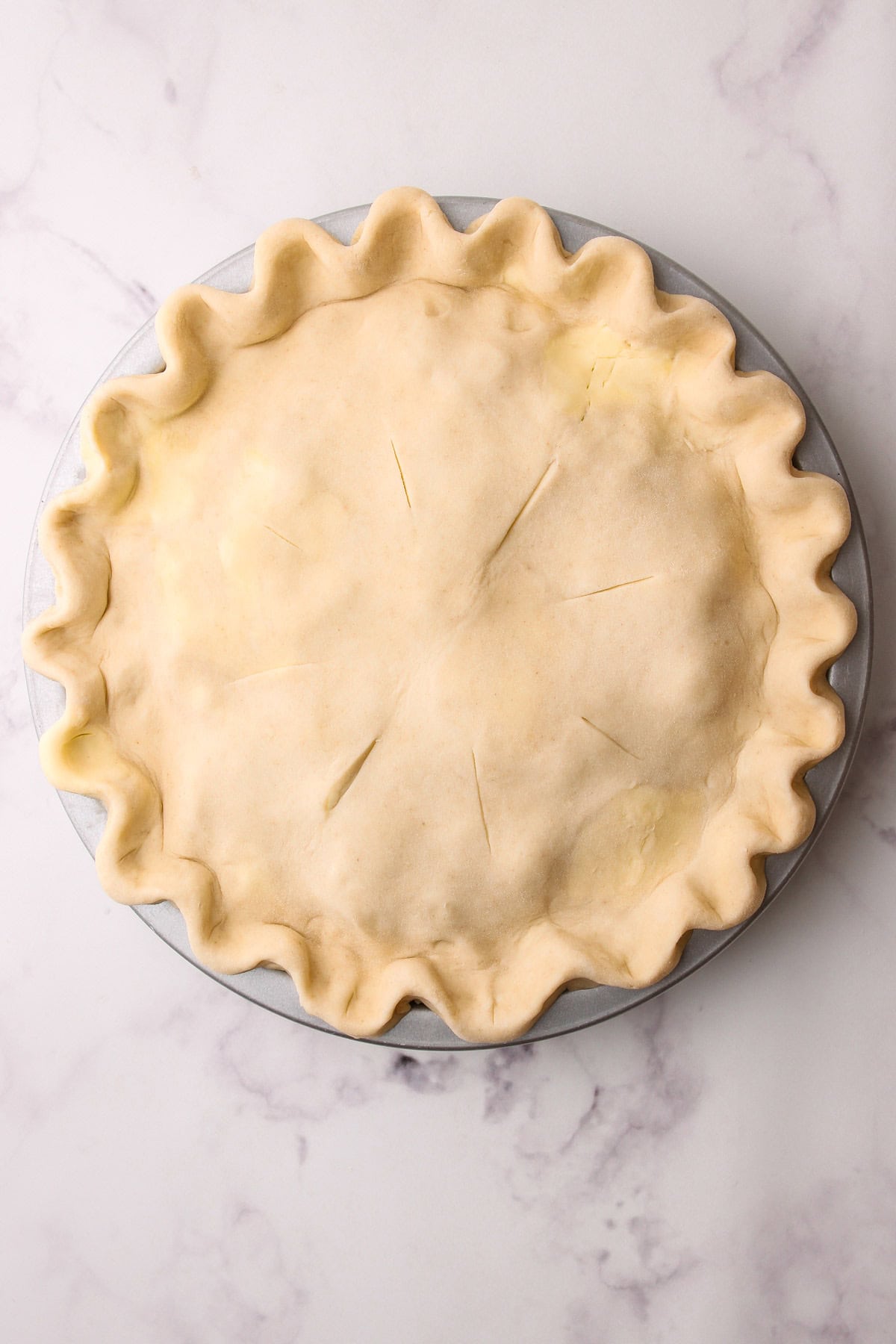 An unbaked peach blueberry pie with a full lattice.