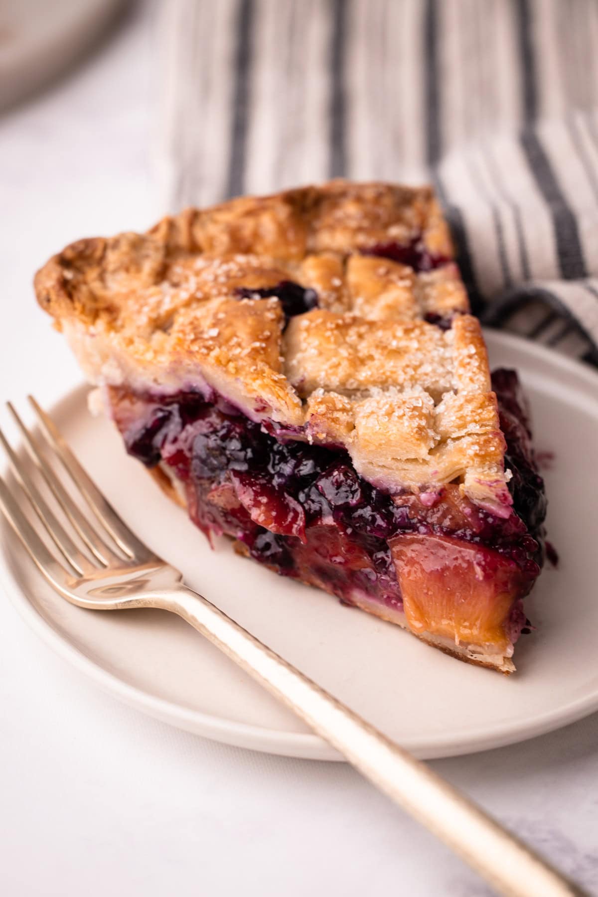 A slice of peach blueberry pie on a plate.