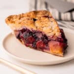 A slice of peach blueberry pie on a plate.