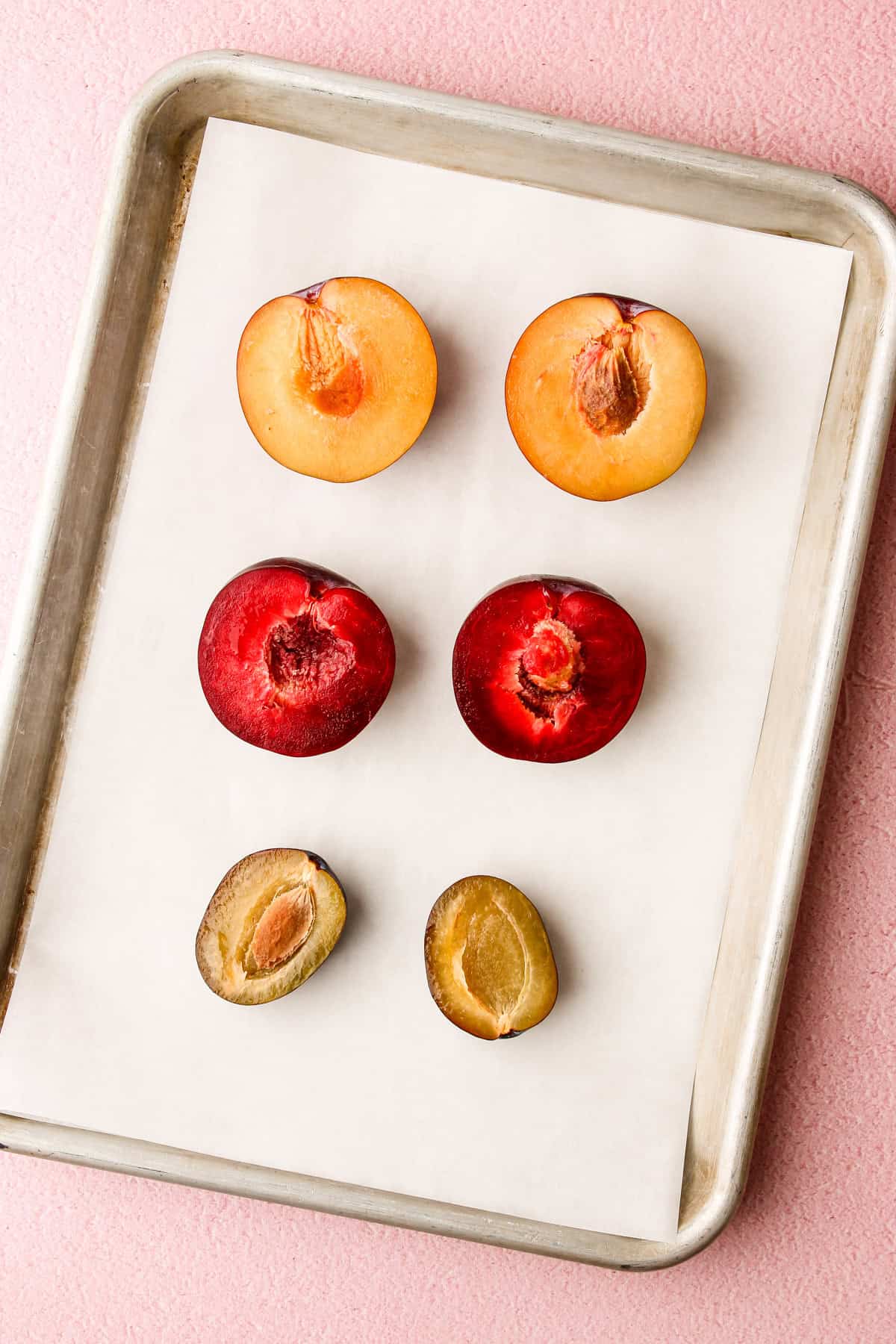 Different types of plums sliced in half to show their differences.