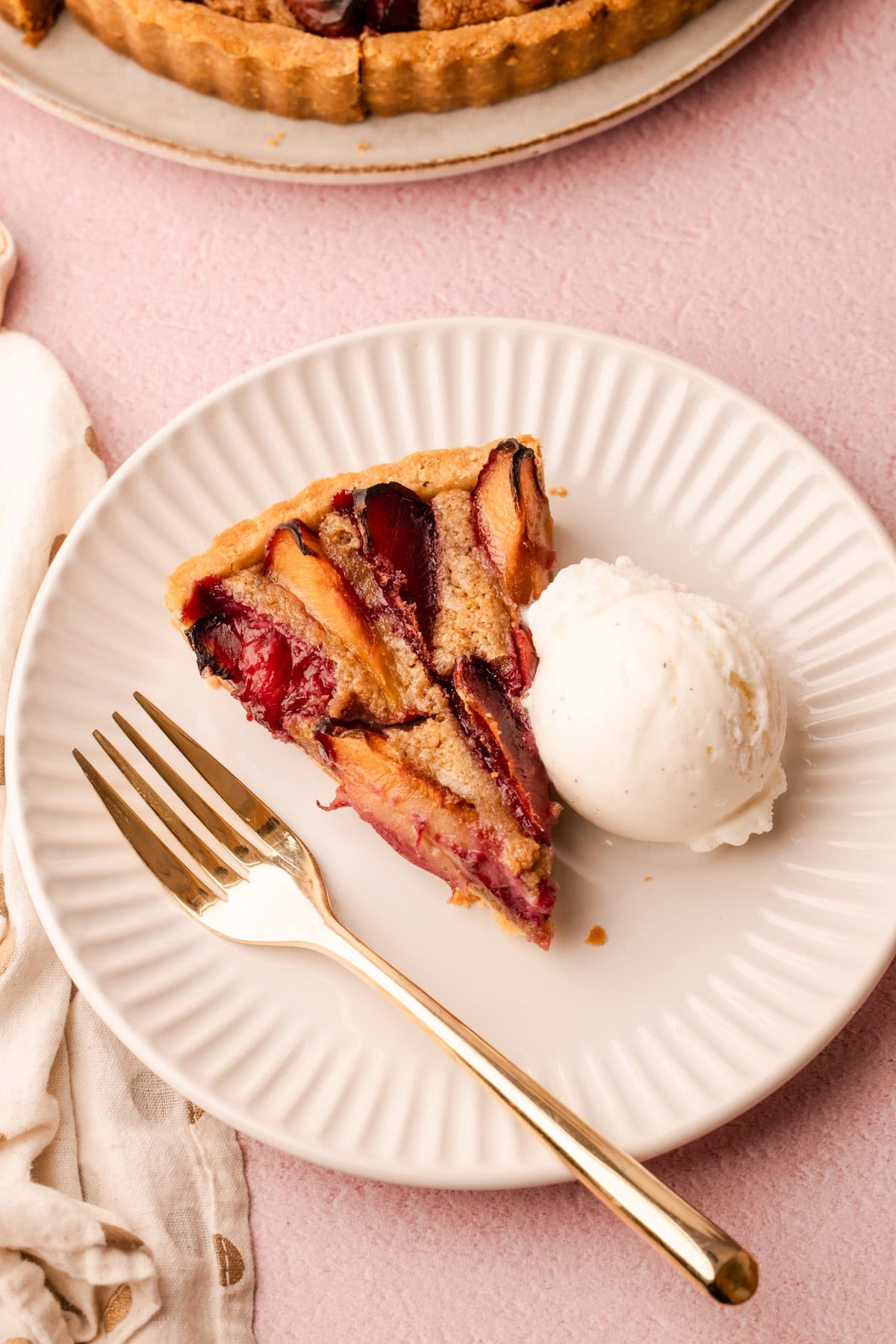 A slice of plum pie on a plate with a scoop of ice cream.
