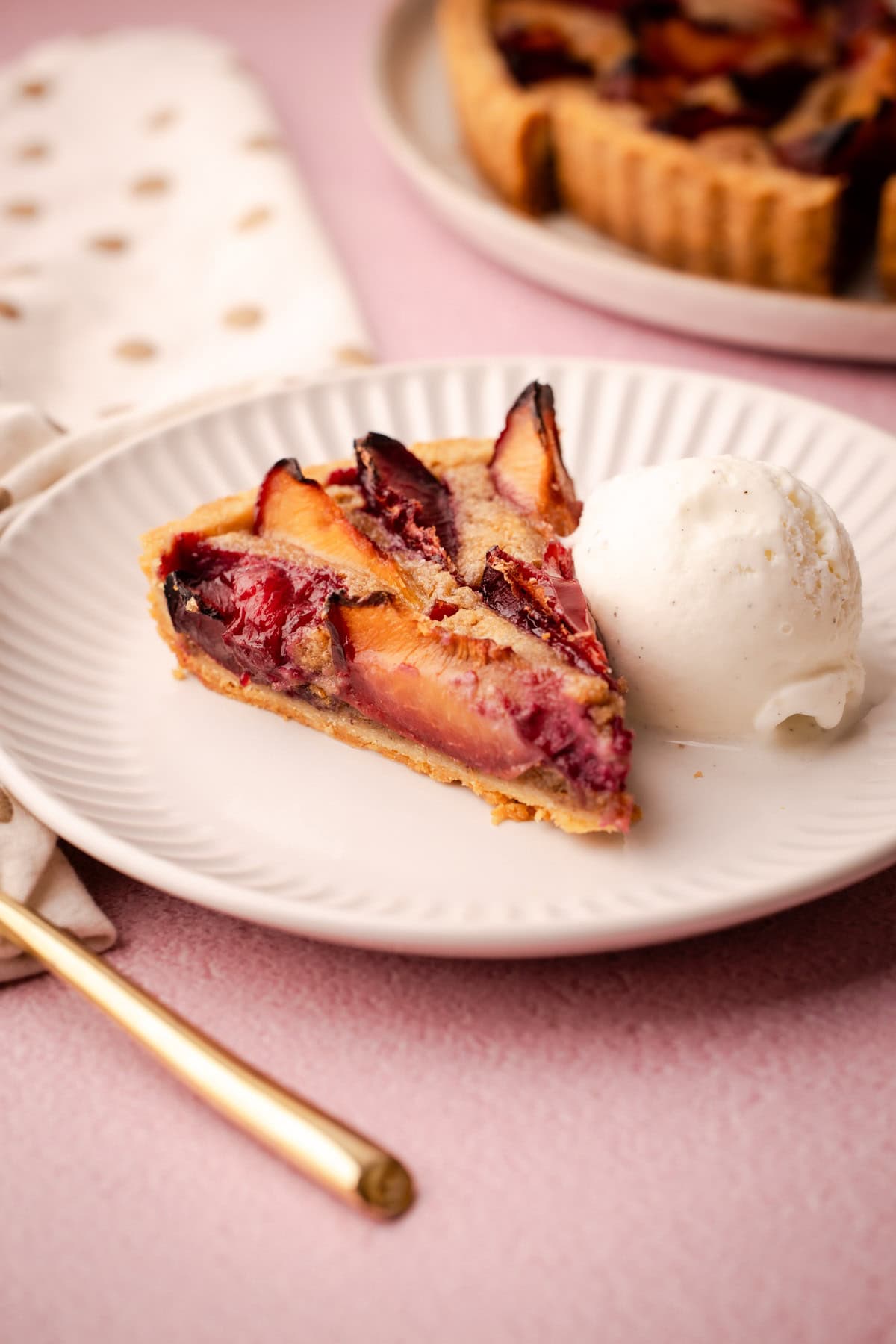 A side view of a slice of plum tart, revealing the walnut frangipane below.