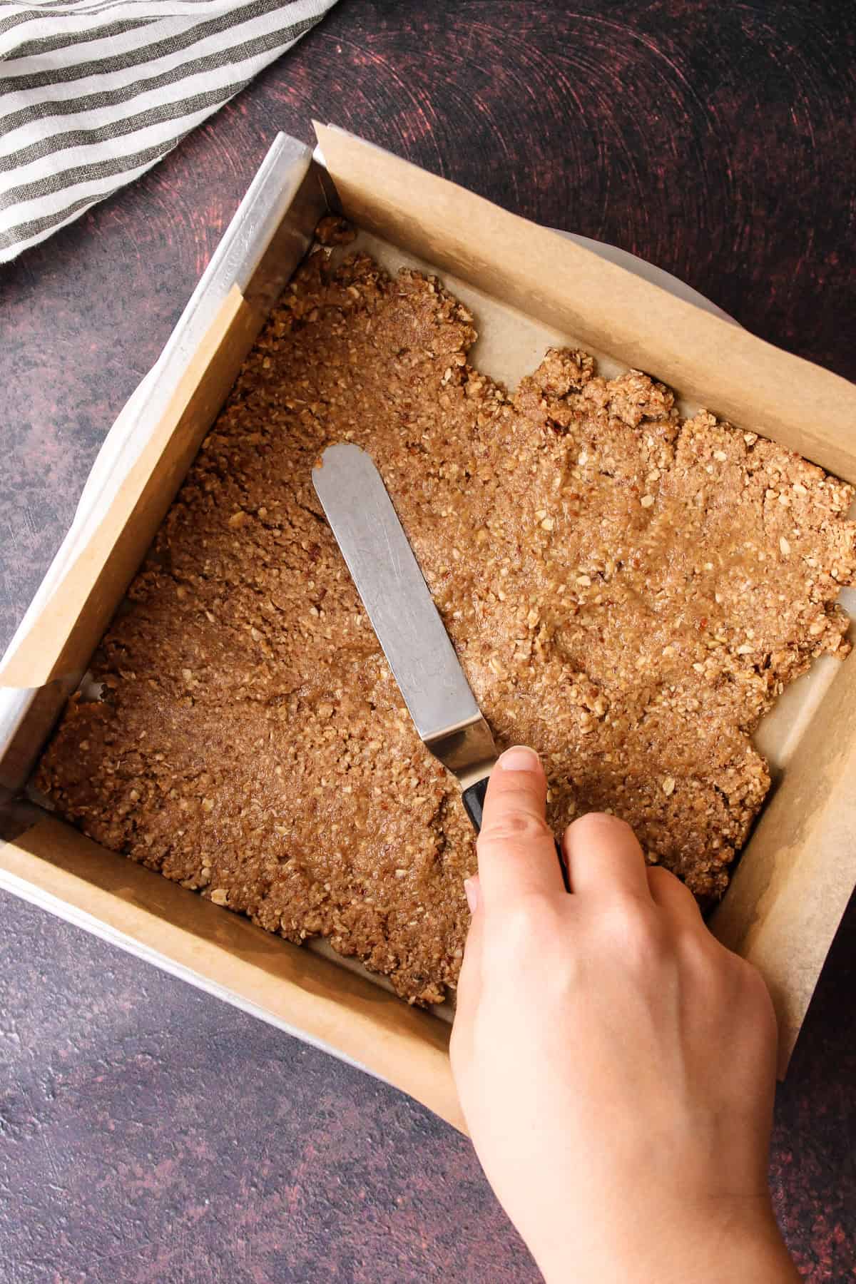 The crumble being added to the baking pan as the crust.