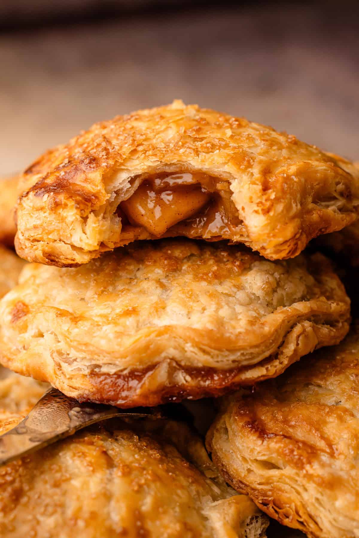 Baked apple hand pies, stacked on top of each other with a bite revealing the apple pie filling inside.
