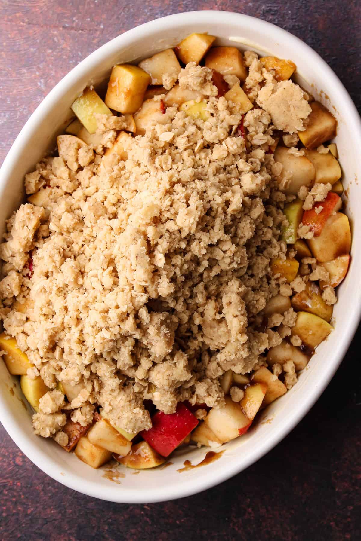 Putting the crumb topping on the apple pear filling in the prepared baking dish.