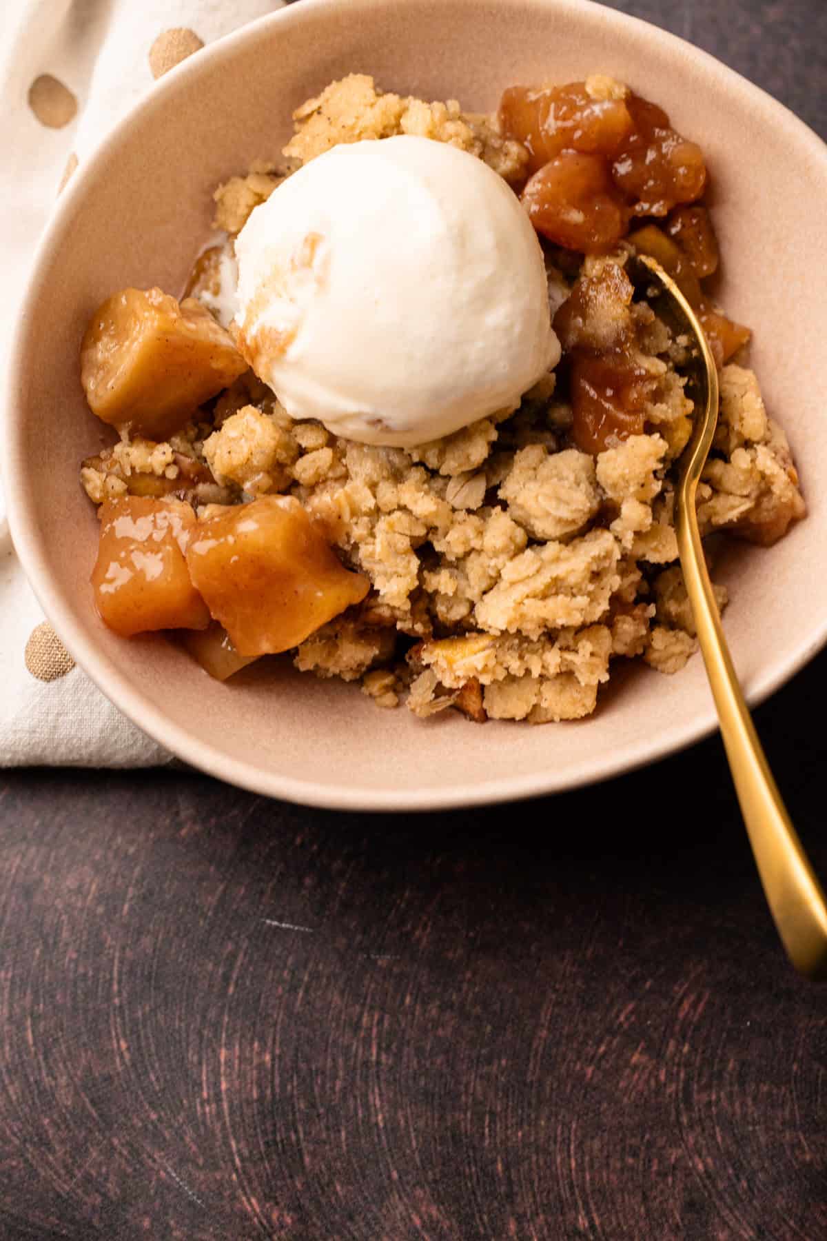 A serving of apple pear crisp with a scoop of ice cream on top.