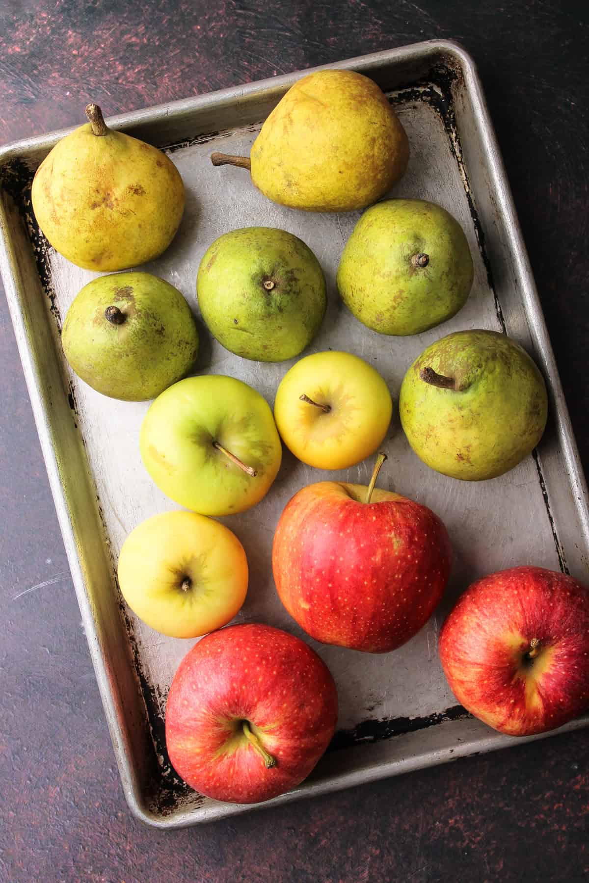 Whole apples and pears on a sheet pan.