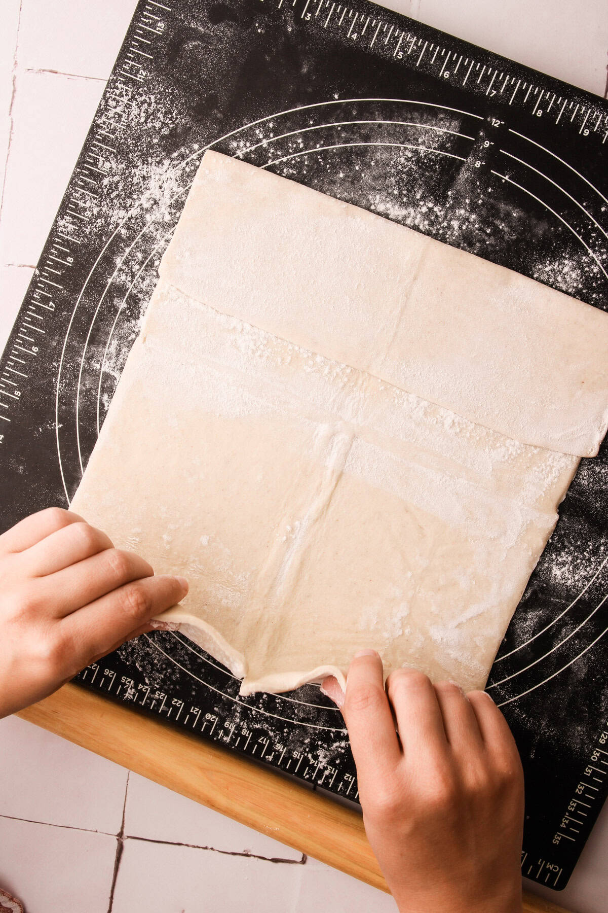 Laying pieces of puff pastry together to form the crust for an apple pie.