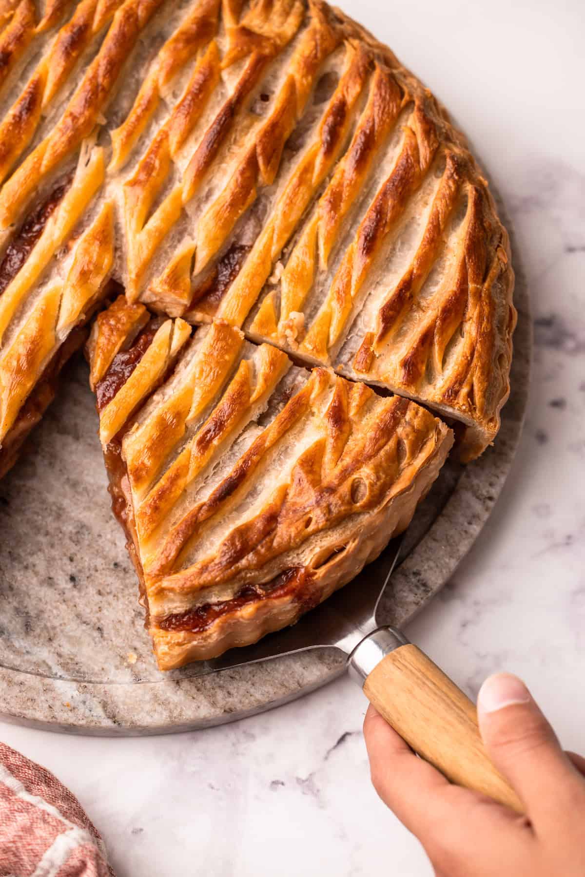 A cut piece of apple pie made with puff pastry on a serving platter.