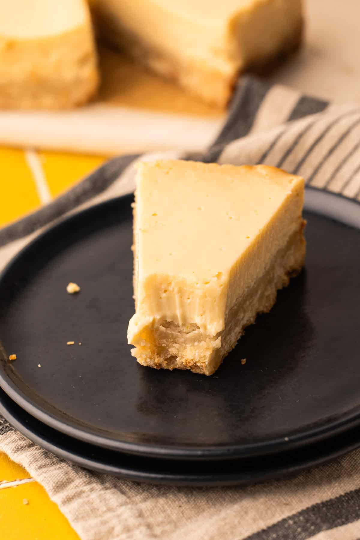 A close up of a lemon pie bar with a thick layer of lemon filling and shortbread crust on a plate.