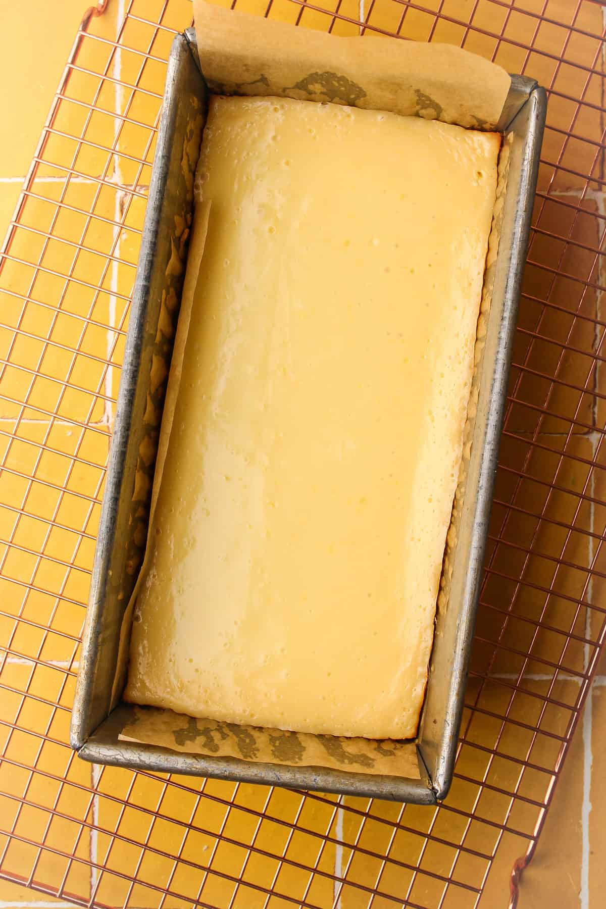 A small batch of creamy lemon pie bars baked and cooling on a baking rack.