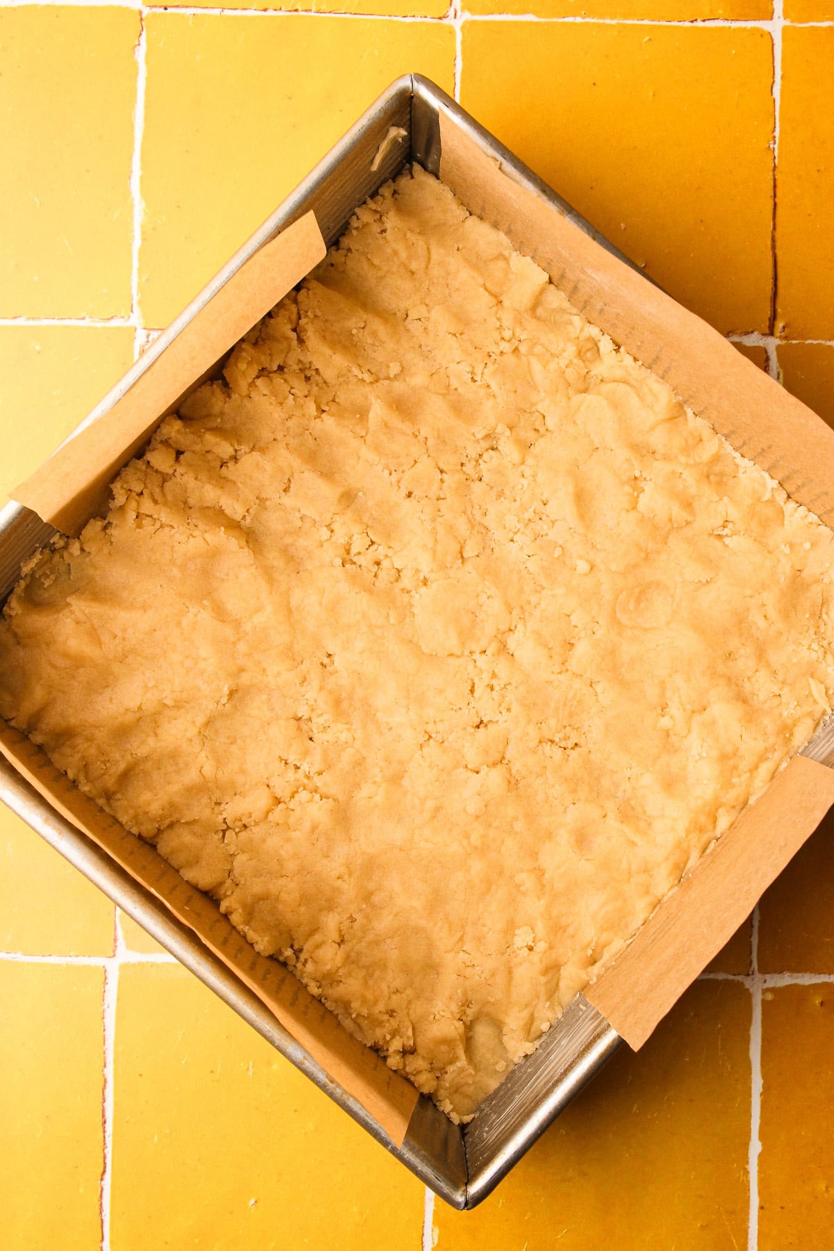 The crust packed inside of a prepared 8" square baking dish, unbaked.