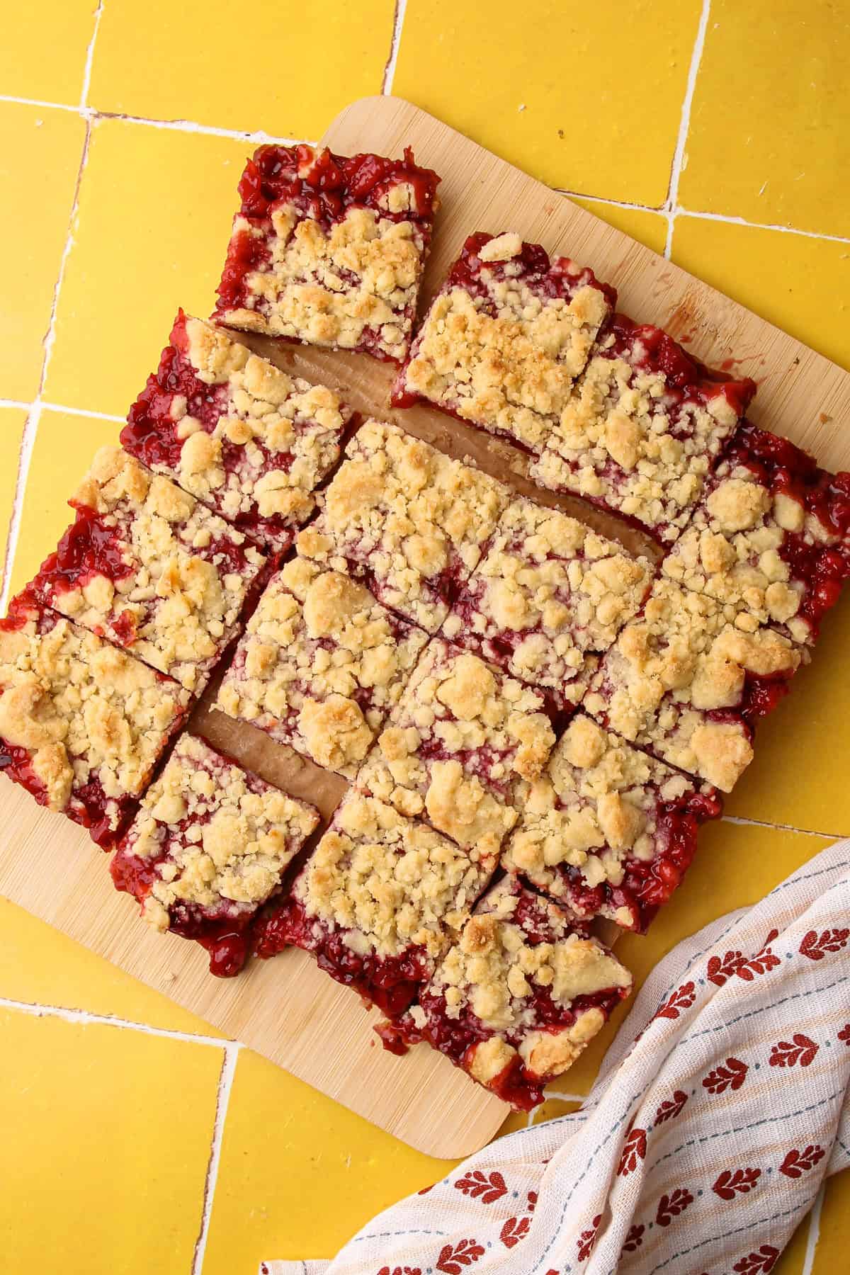Sliced of cherry pie bars arranged on a cutting board.