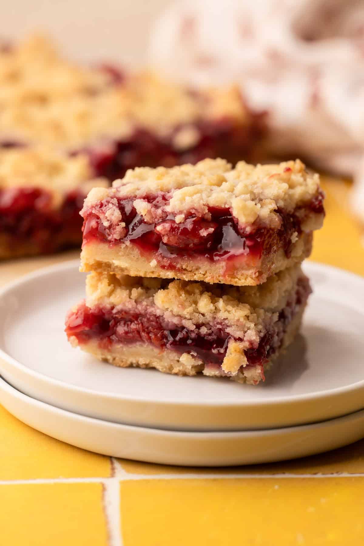 Two baked cherry pie bars sliced and arranged on a plate to show the juicy filling.