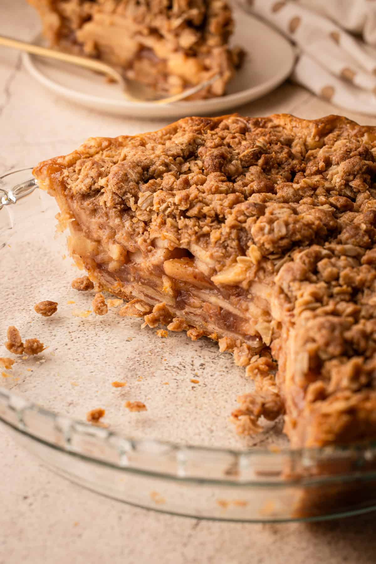 A slice of apple crumb pie showing tightly layered apples beneath an oat topping.