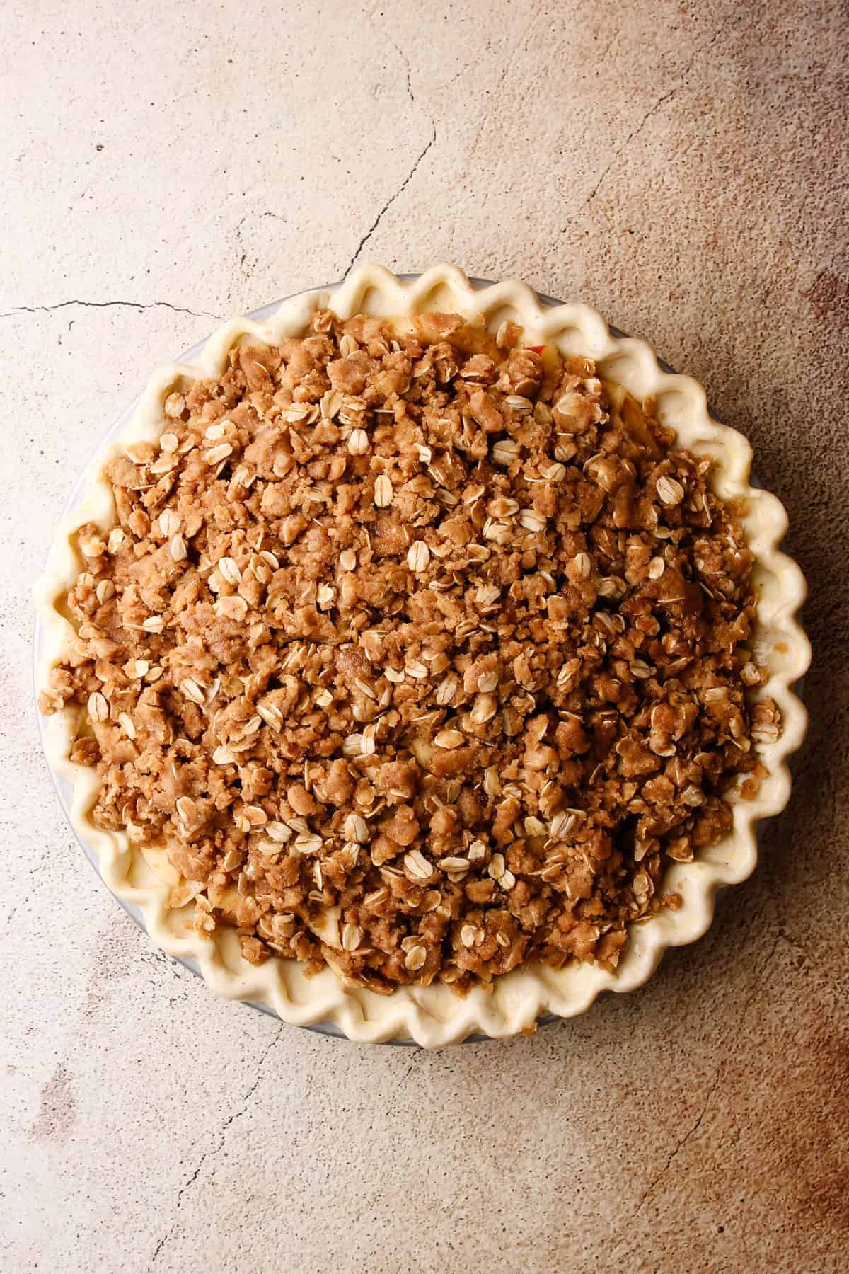 An overhead view of a unbaked apple crumb pie.